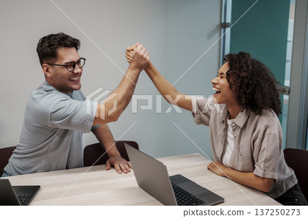Two Professional Colleagues Exchange Lively Fist Bumps To Commemorate Successful Agreement In Workspace Two Professional Colleagues Exchange Lively Fist Bumps To Commemorate Successful Agreement In Workspace 137250273