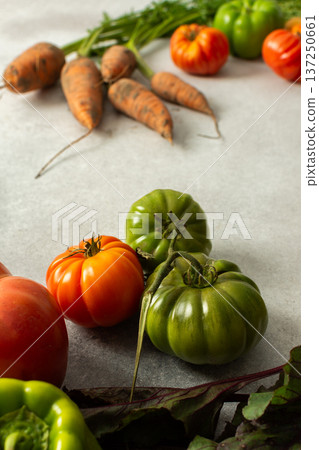 Fresh vegetables from the garden are arranged on a gray surface. The collection includes tomatoes, carrots, beets, and green peppers placed next to each other Fresh vegetables from the garden are arranged on a gray surface. The collection includes tomatoes, carrots, beets, and green peppers placed next to each other 137250661