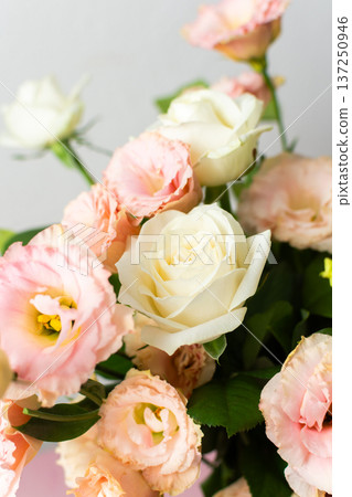 Fresh roses and eustomas are arranged in a bouquet with green leaves. The setting has a plain background and bright lighting. This moment captures floral beauty 137250946