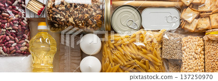 Home food supplies for quarantine and isolation, including canned food, cereals, pasta, and essential staples for survival, survival during military operations, the concept of stay at home, banner Home food supplies for quarantine and isolation, including canned food, cereals, pasta, and essential staples for survival, survival during military operations, the concept of stay at home, banner 137250970
