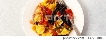 This wholesome breakfast includes black rice with stewed vegetables, stewed tomatoes, zucchini, peppers and onions top view 137251086
