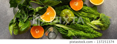 Fresh spinach, chard, and broccoli sit among sliced oranges and tangerines as juice is prepared in a kitchen. The scene captures a vibrant approach to healthy drinking, banner Fresh spinach, chard, and broccoli sit among sliced oranges and tangerines as juice is prepared in a kitchen. The scene captures a vibrant approach to healthy drinking, banner 137251374