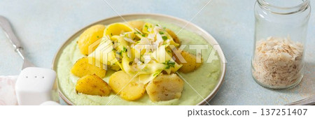 Baked potatoes are topped with slices of fermented zucchini and served alongside a green pea sauce with broccoli. This meal is prepared for a healthy breakfast, banner Baked potatoes are topped with slices of fermented zucchini and served alongside a green pea sauce with broccoli. This meal is prepared for a healthy breakfast, banner 137251407