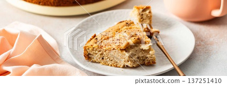 A slice of pear pie sits on a white plate with a fork. A warm coffee cup is next to it. Fresh pears are placed on the table, adding to the scene, banner A slice of pear pie sits on a white plate with a fork. A warm coffee cup is next to it. Fresh pears are placed on the table, adding to the scene, banner 137251410