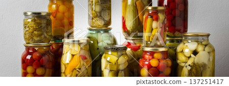 Canning is a common activity in the kitchen as jars filled with vegetables and fruits line the counter. This practice helps in preserving food for winter use and has a long tradition, banner 137251417