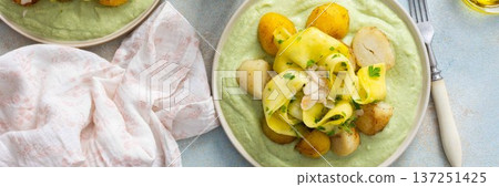 Baked potatoes are topped with fermented zucchini slices and served on a green pea sauce with broccoli for a healthy breakfast option that is hearty, banner 137251425