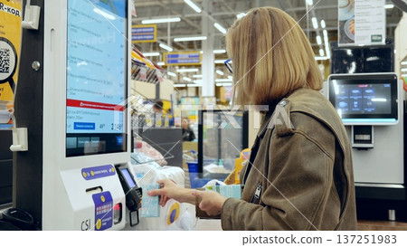 Customer using self service checkout at a high tech supermarket, improving retail efficiency and convenience 137251983
