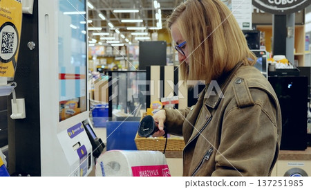 Woman scanning toilet paper at self service checkout in modern supermarket, using barcode scanner and digital touchscreen terminal for faster shopping experience Woman scanning toilet paper at self service checkout in modern supermarket, using barcode scanner and digital touchscreen terminal for faster shopping experience 137251985