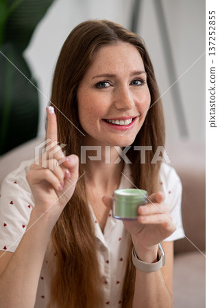 Pretty woman using face cream and looking excited Pretty woman using face cream and looking excited 137252855