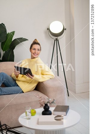 Young woman with tablet in hands lying on the sofa Young woman with tablet in hands lying on the sofa 137252896
