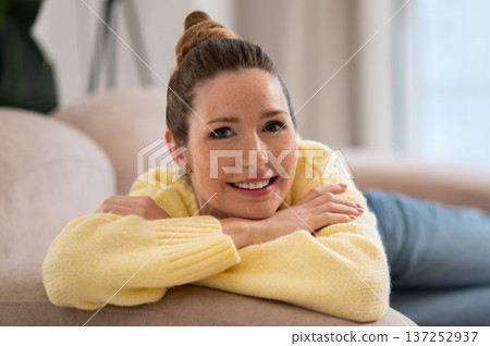 Smiling young woman resting at home and lying on the sofa Smiling young woman resting at home and lying on the sofa 137252937