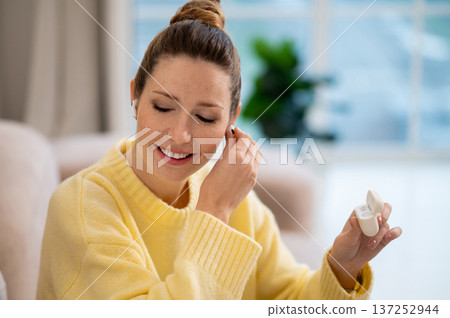 Young woman with hair bun using wireless earphones Young woman with hair bun using wireless earphones 137252944