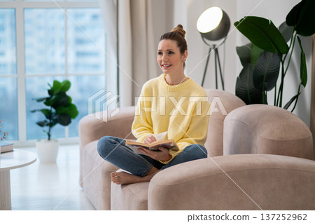 Woman sitting in the armchair and reading a book Woman sitting in the armchair and reading a book 137252962