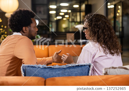 Woman discussing with colleague while sitting on sofa Woman discussing with colleague while sitting on sofa 137252985