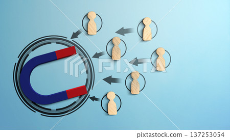 A blue and red horseshoe magnet attracting wooden peg figures representing people or customers. This conceptual image illustrates lead generation, recruitment, and marketing attraction A blue and red horseshoe magnet attracting wooden peg figures representing people or customers. This conceptual image illustrates lead generation, recruitment, and marketing attraction 137253054