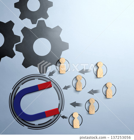 A conceptual image featuring a horseshoe magnet attracting wooden human figurines. Gears in the background and arrows symbolise business processes, marketing strategies, and lead generation 137253056