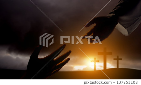 A dramatic silhouette of a hand reaching down from above to meet a hand reaching up, set against a backdrop of three crosses on a hill. Represents faith, salvation, and divine intervention 137253108