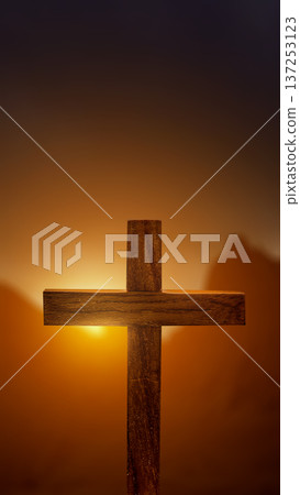 A simple wooden cross stands against a warm, glowing sunset. The soft golden light creates a spiritual and peaceful atmosphere, representing faith, hope, and redemption in Christianity A simple wooden cross stands against a warm, glowing sunset. The soft golden light creates a spiritual and peaceful atmosphere, representing faith, hope, and redemption in Christianity 137253123