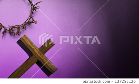 A wooden cross and crown of thorns rest on a textured purple background with a dark gradient. This symbolizes the Passion of Christ, and Good Friday, featuring copy space for religious messages A wooden cross and crown of thorns rest on a textured purple background with a dark gradient. This symbolizes the Passion of Christ, and Good Friday, featuring copy space for religious messages 137253126