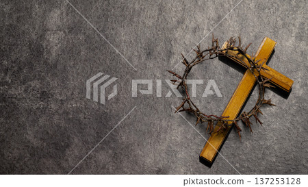 A wooden cross and crown of thorns symbolizing the passion of Christ on a dark stone surface. The composition includes significant copy space for religious messages, Easter, and Good Friday themes A wooden cross and crown of thorns symbolizing the passion of Christ on a dark stone surface. The composition includes significant copy space for religious messages, Easter, and Good Friday themes 137253128