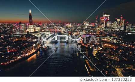 England, London: Illuminated London skyline at sunset, Tower Bridge over Thames River and The Shard in a stunning urban night lights. Aerial view drone flight over famous UK capital tourist landmarks England, London: Illuminated London skyline at sunset, Tower Bridge over Thames River and The Shard in a stunning urban night lights. Aerial view drone flight over famous UK capital tourist landmarks 137253233