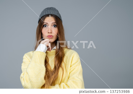 Pretty young woman in grey hat feeling astonished 137253986