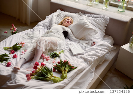 Woman relaxing with flowers and props, Sunlit setting featuring woman with floral arrangements and decor Woman relaxing with flowers and props, Sunlit setting featuring woman with floral arrangements and decor 137254136