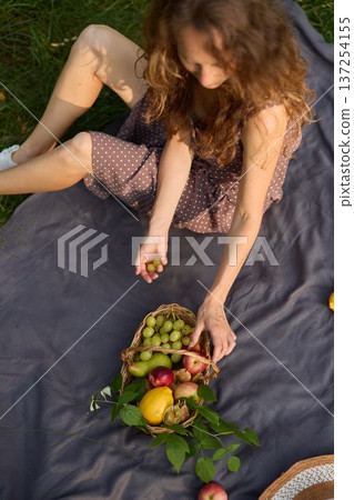 Rustic picnic scene with woman preparing fresh fruit outdoors 137254155