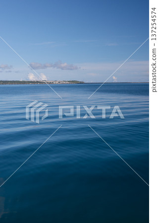 平靜的藍色大海，遠處地平線上隱約可見一座島嶼的輪廓。 137254574