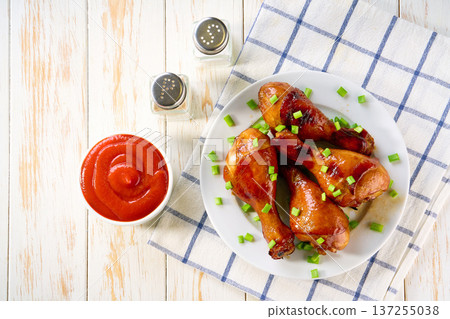 Grilled chicken drumsticks with sauce on a white table, top view. Grilled chicken drumsticks with sauce on a white table, top view. 137255038