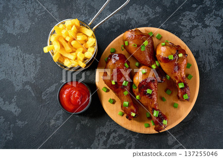 Fried crispy chicken legs with ketchup and french fry on a black table, top view. Fried crispy chicken legs with ketchup and french fry on a black table, top view. 137255046