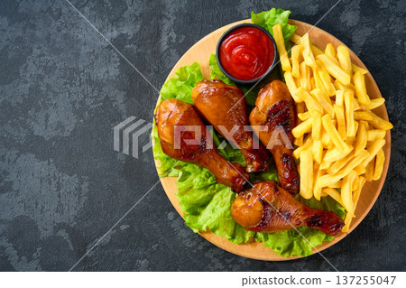 Fried crispy chicken legs with ketchup and french fry on a black table, top view. 137255047