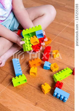 Child building colorful blocks on wooden floor Child building colorful blocks on wooden floor 137255393