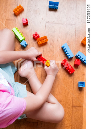 Child playing with colorful building blocks on a wooden floor Child playing with colorful building blocks on a wooden floor 137255405