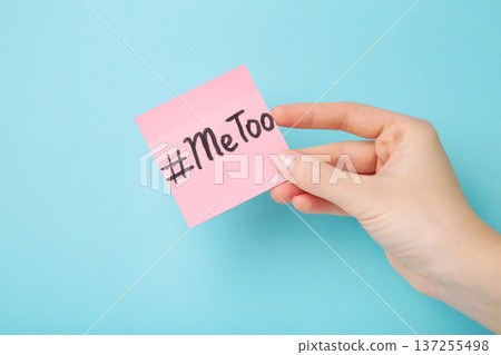 Woman holding white paper with hashtag METOO on blue background. Woman holding white paper with hashtag METOO on blue background. 137255498