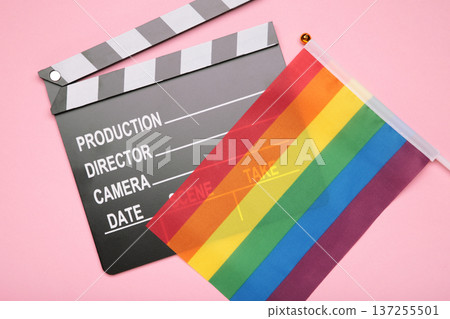 A rainbow flag and black clapperboard on pink background. Top view. A rainbow flag and black clapperboard on pink background. Top view. 137255501