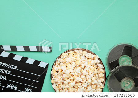 Movie clapper with popcorn and film reels on mint background 137255509