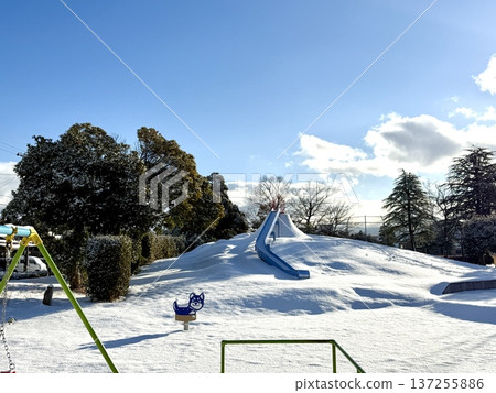Snow-covered morning park with a slide on the hill 137255886