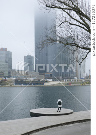 Solitary woman gazing at the urban waterfront from the platform Solitary woman gazing at the urban waterfront from the platform 137256373