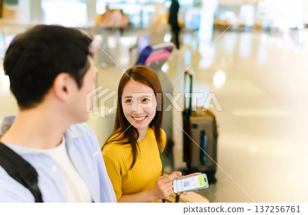 A couple showing their smartphones at the airport. Photo courtesy of Kansai International Airport (KIX) 137256761