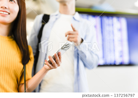 Two people checking their smartphones at the airport ■ Photo courtesy: Kansai International Airport (KIX) Two people checking their smartphones at the airport ■ Photo courtesy: Kansai International Airport (KIX) 137256797