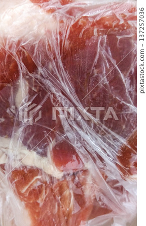 A piece of pork in cellophane. 137257036