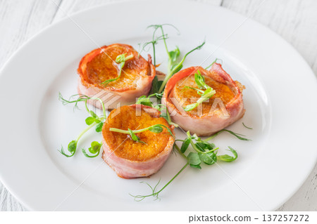 King oyster mushrooms wrapped in crispy bacon served as elegant gourmet appetizer on white plate King oyster mushrooms wrapped in crispy bacon served as elegant gourmet appetizer on white plate 137257272