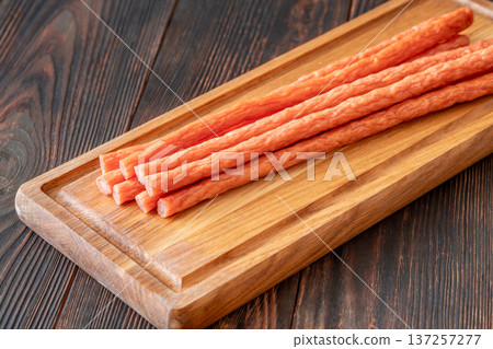 Smoked kabanos sausages arranged on rustic wooden board showcasing traditional savory meat snack texture Smoked kabanos sausages arranged on rustic wooden board showcasing traditional savory meat snack texture 137257277