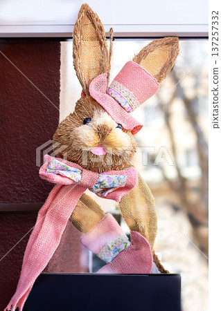 Easter bunny decoration with pink hat and scarf, cheerful spring window ornament Easter bunny decoration with pink hat and scarf, cheerful spring window ornament 137257332