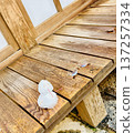 A small snowman and glasses on a wooden bench 137257334