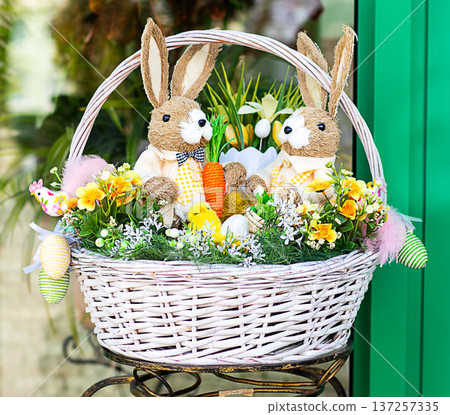 Easter bunny basket with plush rabbit, eggs, flowers and spring decoration for holiday display Easter bunny basket with plush rabbit, eggs, flowers and spring decoration for holiday display 137257335