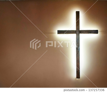 Wooden cross illuminated on church wall, symbol of faith, Easter hope and quiet devotion Wooden cross illuminated on church wall, symbol of faith, Easter hope and quiet devotion 137257336