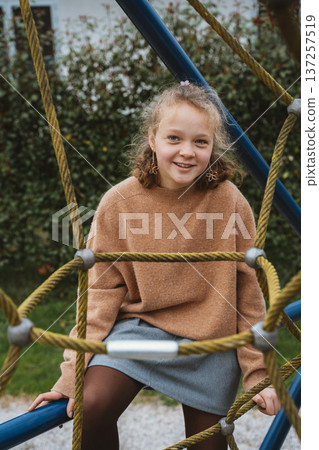 Smiling Child Sitting on Playground Rope Structure Smiling Child Sitting on Playground Rope Structure 137257519