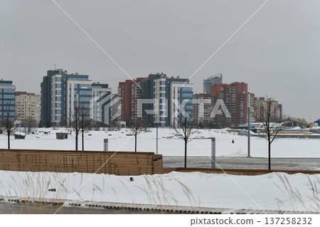 Snowblanketed riverside apartment complex, muted skyline 137258232